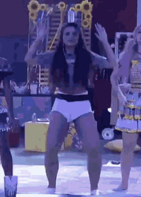 a woman in white shorts is dancing on a stage with other women .
