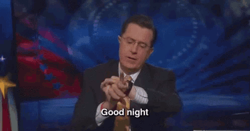 a man in a suit and tie is sitting in front of a microphone and saying good night .