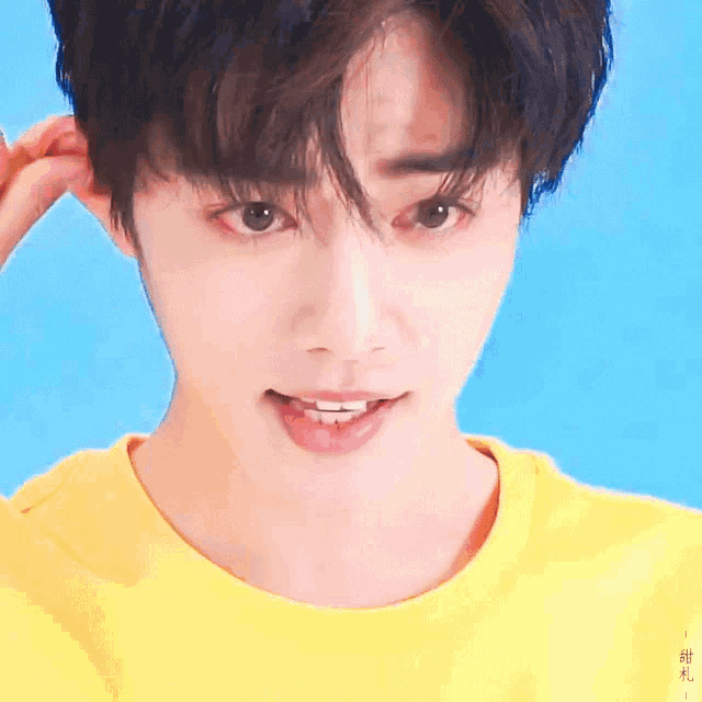 a close up of a young man 's face with a yellow shirt on