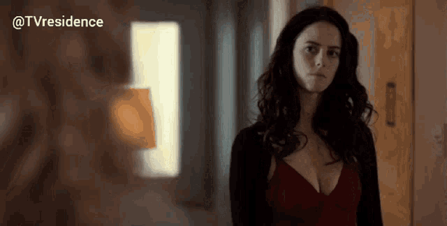 a woman in a red dress is standing in a hallway looking at something .