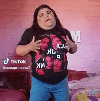 a woman wearing a t-shirt with a picture of a woman on it is standing in front of a bed .