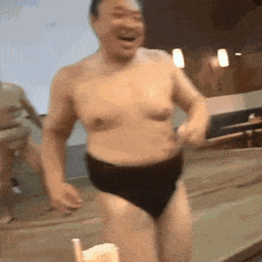 a shirtless man wearing black underwear is running