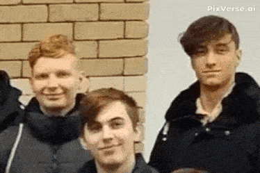 a group of young men are standing next to each other and smiling in front of a brick wall .