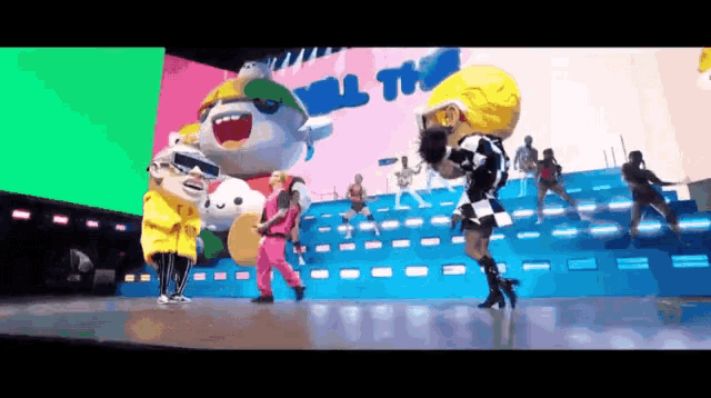 a group of people dancing on a stage with a sign that says " all the " in the background