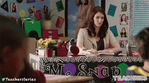 a woman is sitting at a desk in front of a sign that says ms snap teachers