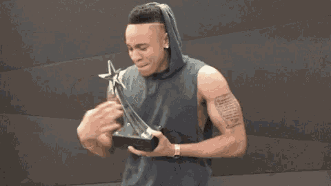 a man with tattoos on his arm is holding a trophy