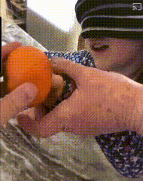 a person wearing a hat is holding an orange