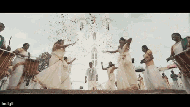 a group of people are dancing in front of a white building