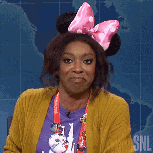 a woman wearing minnie mouse ears and a snl lanyard makes a funny face