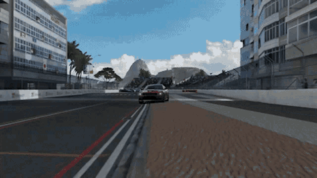 a red car is driving down a race track in front of a building that says microsoft