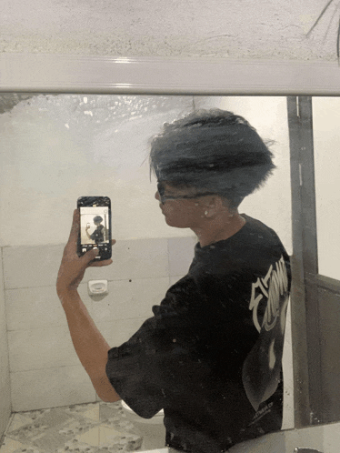 a man in a black shirt taking a picture of himself in a mirror