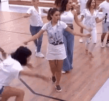 a group of women are dancing on a wooden floor