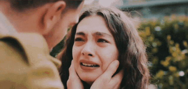 a man is touching a woman 's face while she cries