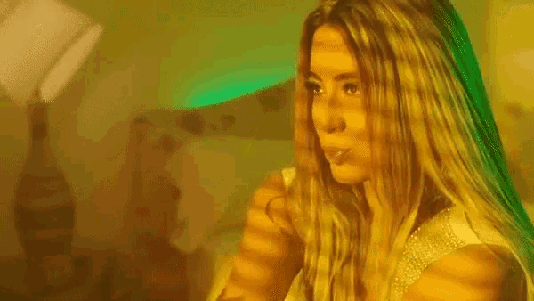 a woman is blowing a kiss while sitting on a bed in a room .