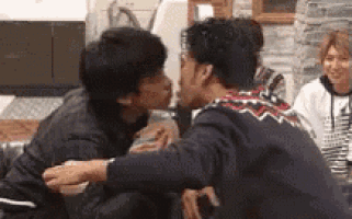 two men are kissing each other while sitting on a couch in a living room .