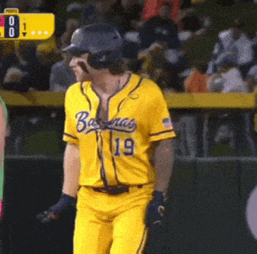 a baseball player wearing a yellow jersey with the number 19 on it is walking on the field .
