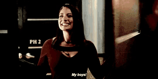a woman holding a bottle of wine and saying my boys