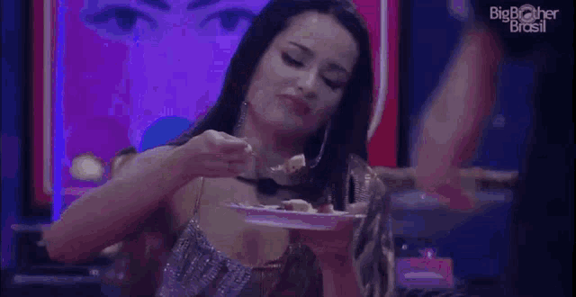 a woman is holding a plate of food in her hand and eating it .