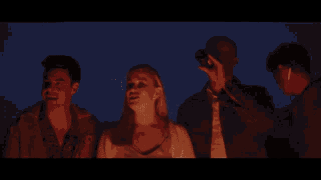 a group of people are gathered around a fire at night