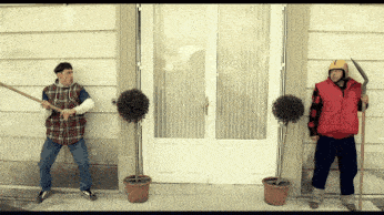 a man in a red vest holds a scythe in front of a door