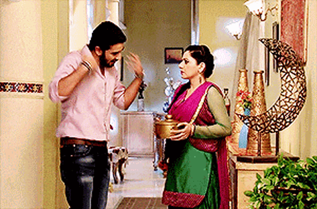 a man and a woman are standing in a hallway and the woman is holding a pot