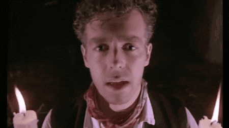 a man with curly hair is holding two lit candles in his hands .
