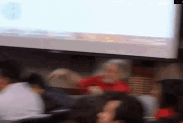 a blurry picture of people sitting in front of a screen