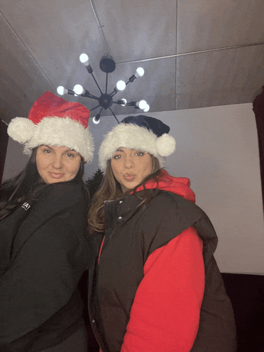 two women wearing santa hats are posing for a photo