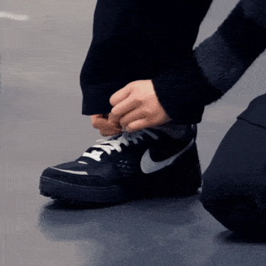 a person is tying their black nike shoes