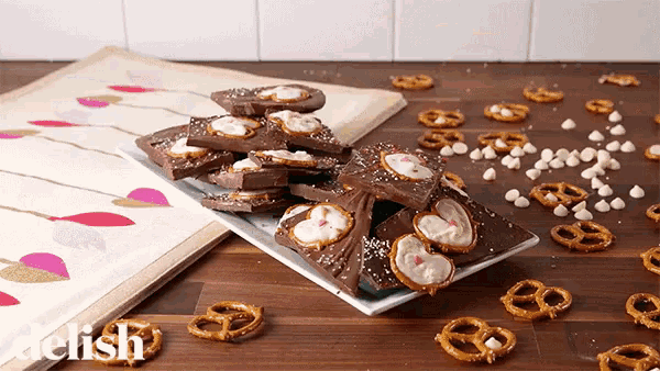 a plate of chocolate and pretzels on a wooden table with the word kelish on the bottom
