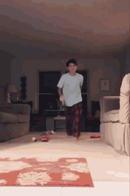 a man in a white shirt and plaid pants is standing in a living room