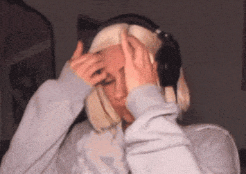 a woman wearing headphones is holding her head in pain