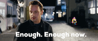 a man is standing on a street with the words `` enough enough now '' written on the bottom of the image .