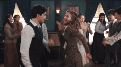 a man and a woman are dancing in a room surrounded by people