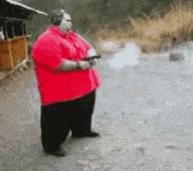 a man in a red shirt is holding a gun and wearing headphones
