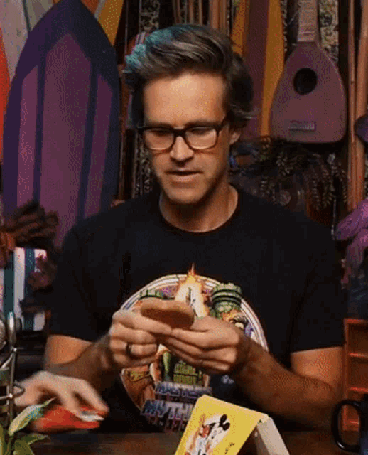 a man wearing glasses and a shirt that says ' hawaii ' on it is looking at his phone