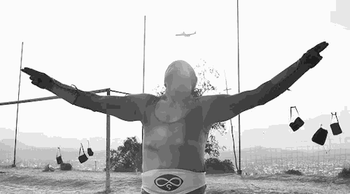 a black and white photo of a man with his arms outstretched in front of a volleyball net