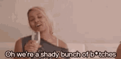 a woman is holding a glass of wine and saying `` oh we 're a shady bunch of bitches ''