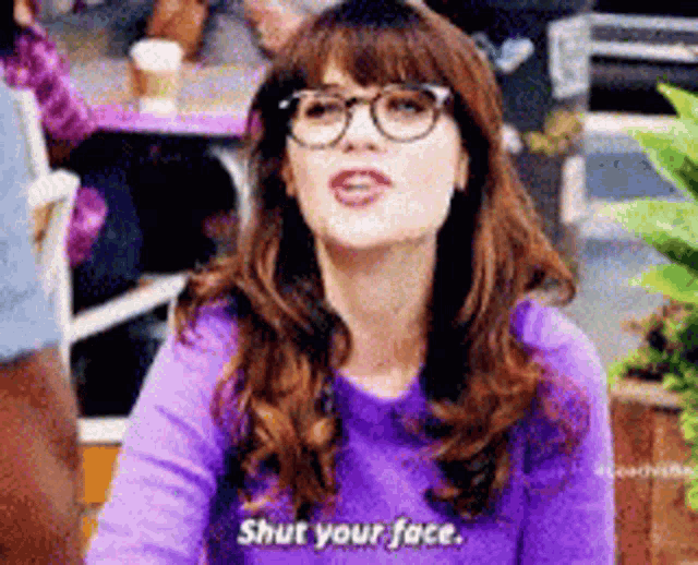 a woman wearing glasses and a purple sweater is saying shut your face