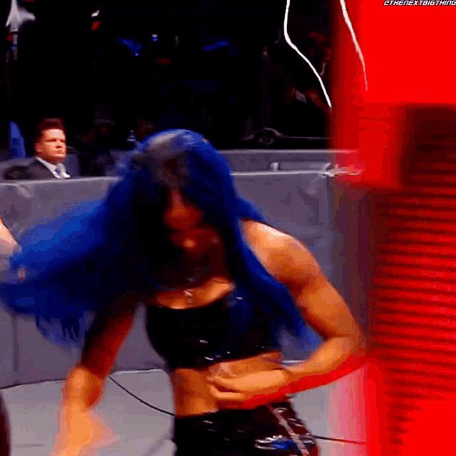 a woman with blue hair is standing in front of a red wall that says thenextbigthing