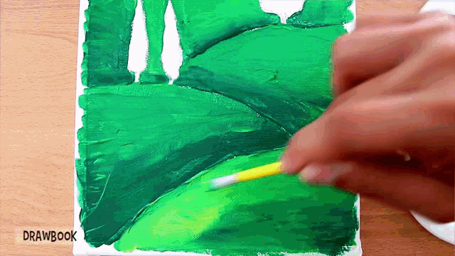 a person is painting a green leaf with drawbook written on the bottom right