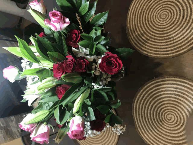 a bouquet of pink and red roses sits on a table next to a striped rug