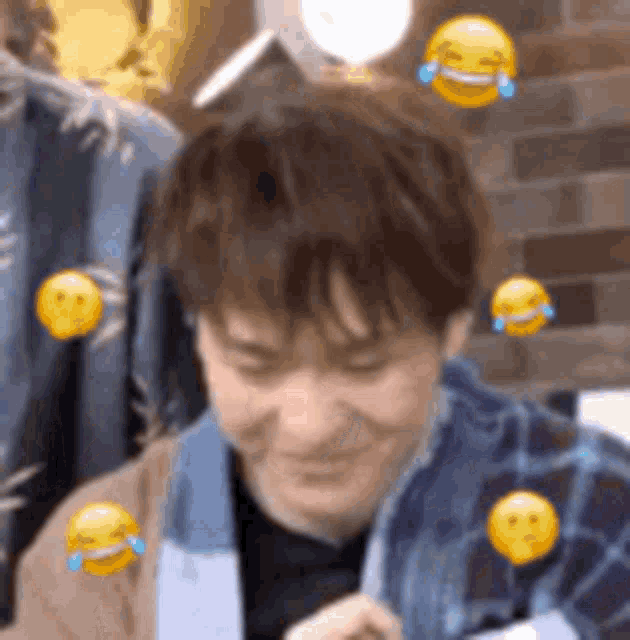 a man is sitting in front of a brick wall with smiley faces around his head .