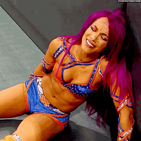 a female wrestler with purple hair is laying on the floor