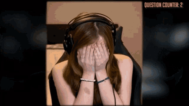 a woman wearing headphones covering her face with her hands in front of a question counter that reads question counter 2