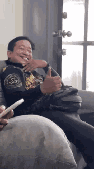 a man sitting on a couch with a thumbs up
