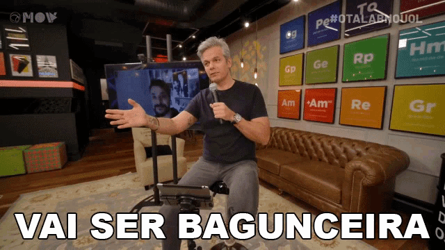a man sitting in front of a couch with the words vai ser baguncera written on the bottom