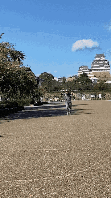 a person walking on a gravel road in front of a large building