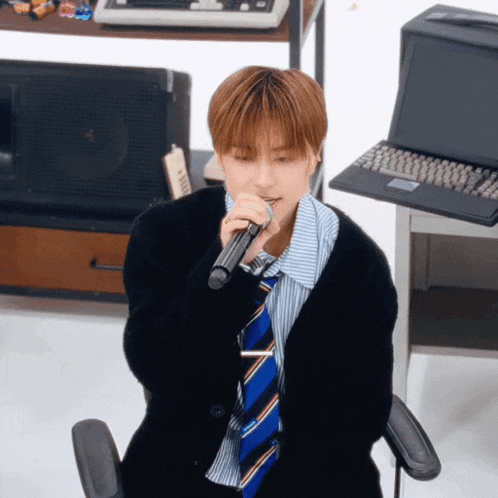 a man singing into a microphone in front of a computer
