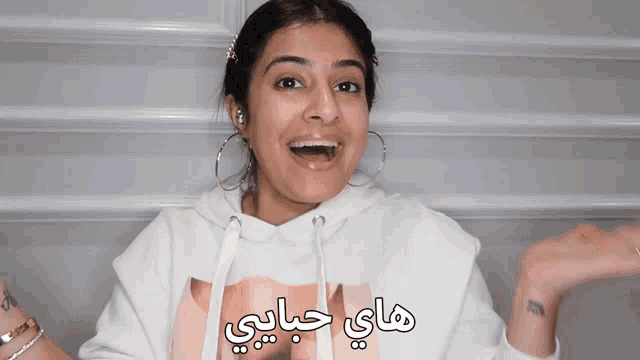 a woman wearing a white hoodie with arabic writing